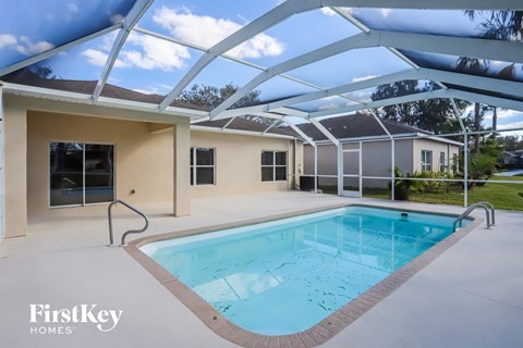 A swimming pool is in the middle of a patio area.