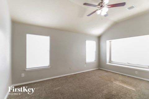 a living room with two windows and a ceiling fan