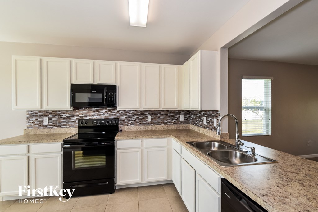 a kitchen with white cabinets and granite counter tops and black appliances