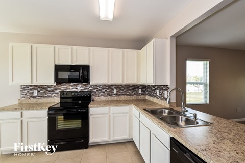 a kitchen with white cabinets and granite counter tops and black appliances