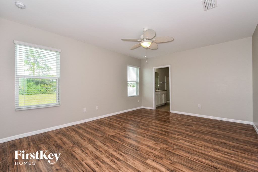 the spacious living room with hardwood flooring and a ceiling fan