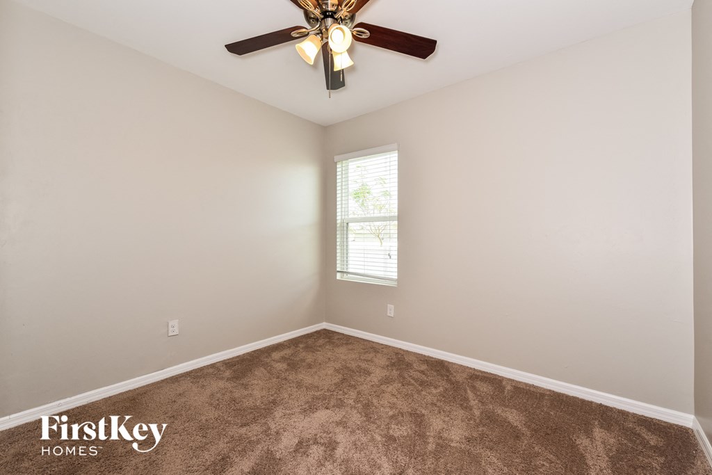 a bedroom with a ceiling fan and a carpet