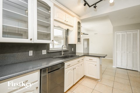 a kitchen with white cabinets and a sink and a window