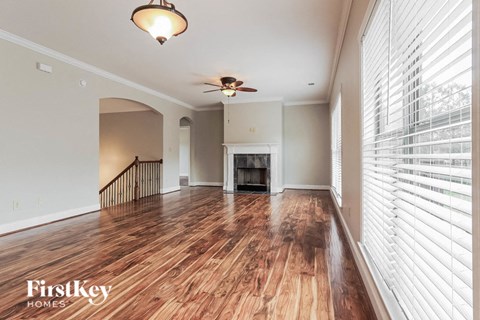 A spacious living room with wood flooring and a ceiling fan.
