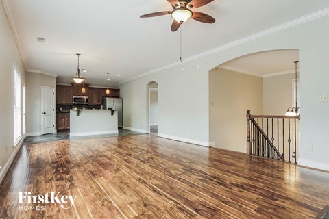 A spacious room with wooden floors and a ceiling fan.