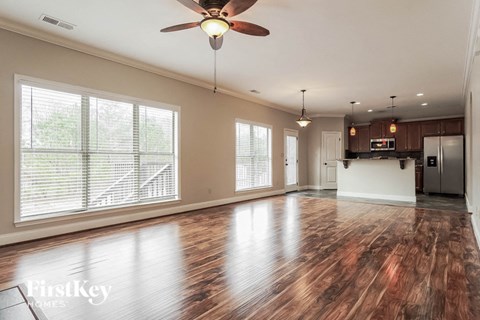 A spacious room with wooden floors and a ceiling fan.