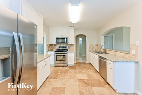 A kitchen with a tile floor and a refrigerator.