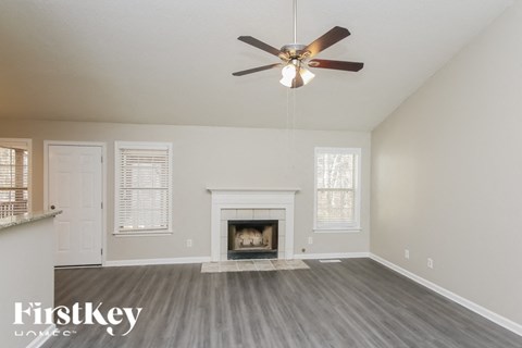 A spacious room with a fireplace and a ceiling fan.