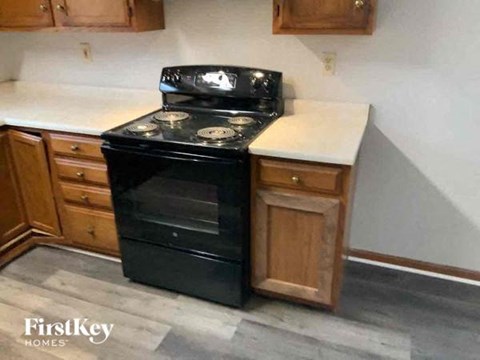 A black stove top oven with four burners is in a kitchen with wooden cabinets.