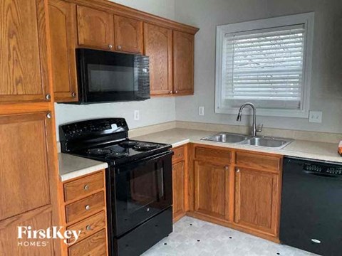 A kitchen with wooden cabinets and black appliances.