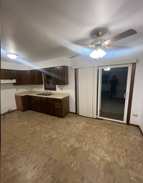 A kitchen with a fan and brown cabinets.