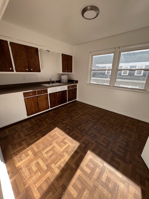 an empty kitchen with wood flooring in an empty apartment