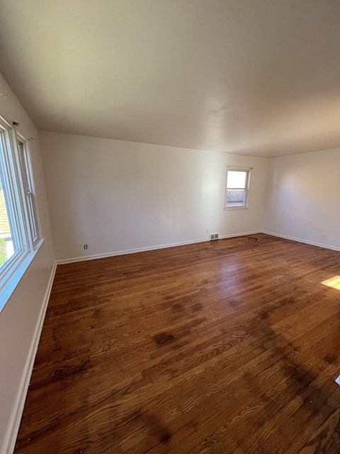an empty living room with wooden floors and a window