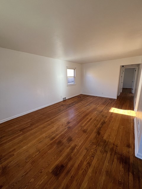 an empty living room with wooden floors and a window