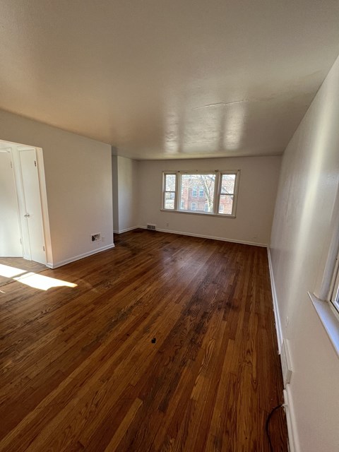 an empty living room with wooden floors and a window