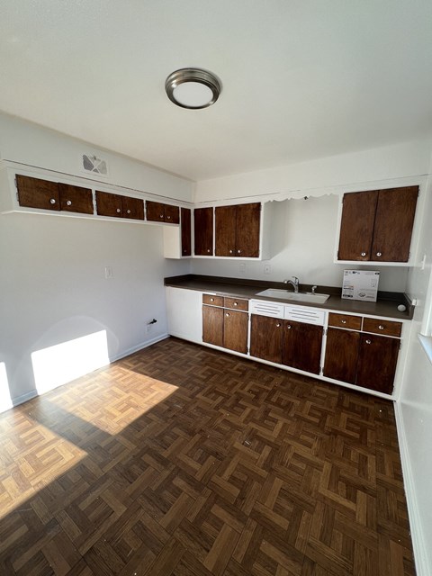 an empty kitchen with wooden floors and wooden cabinets