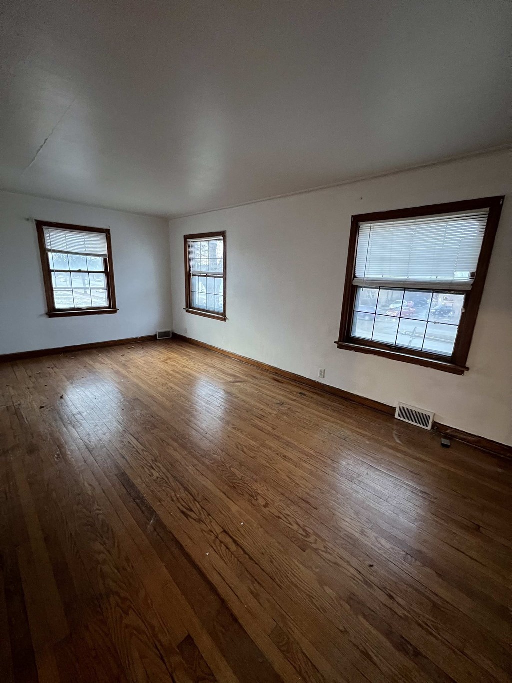 an empty living room with wood floors and two windows
