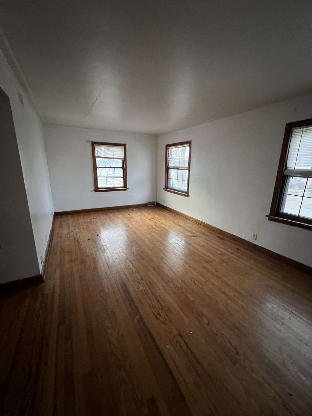 an empty living room with wooden floors and two windows