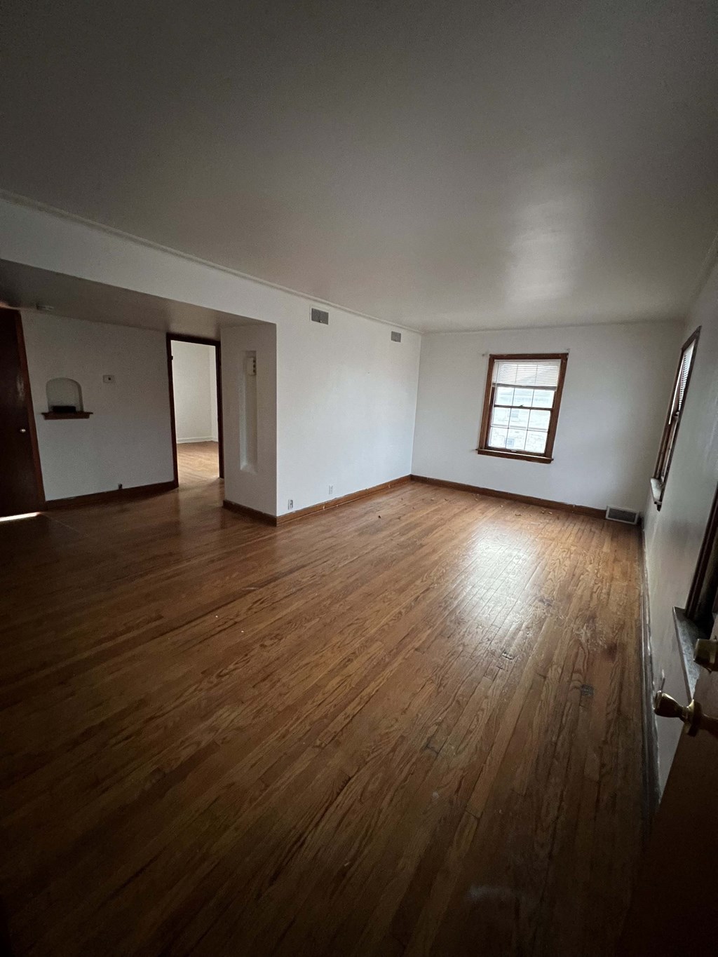 an empty living room with wooden floors and a window