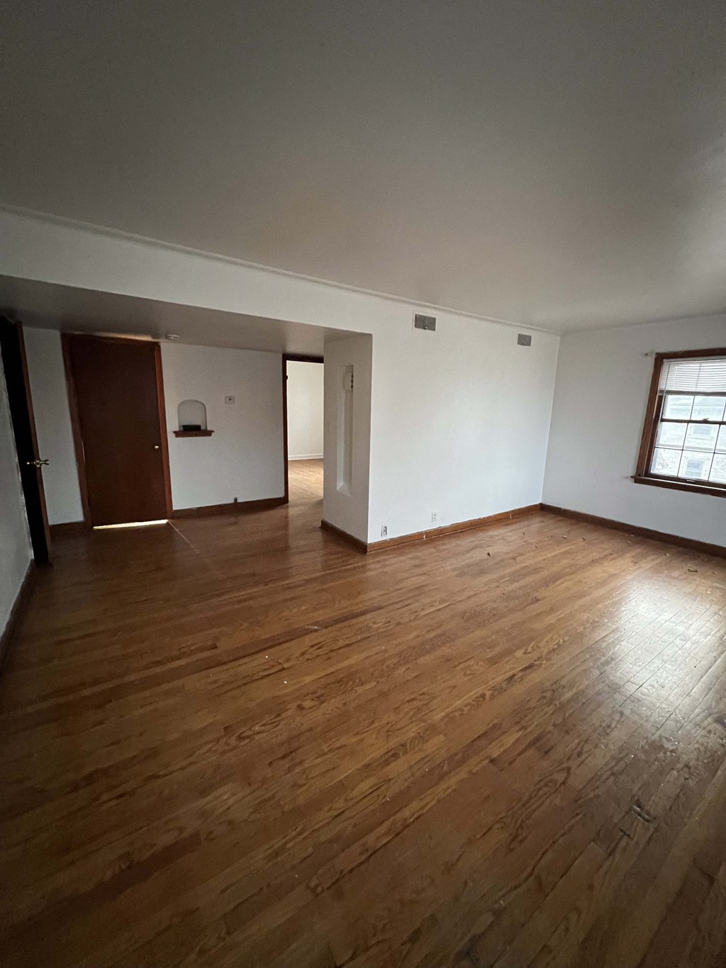 an empty living room with white walls and wooden floors
