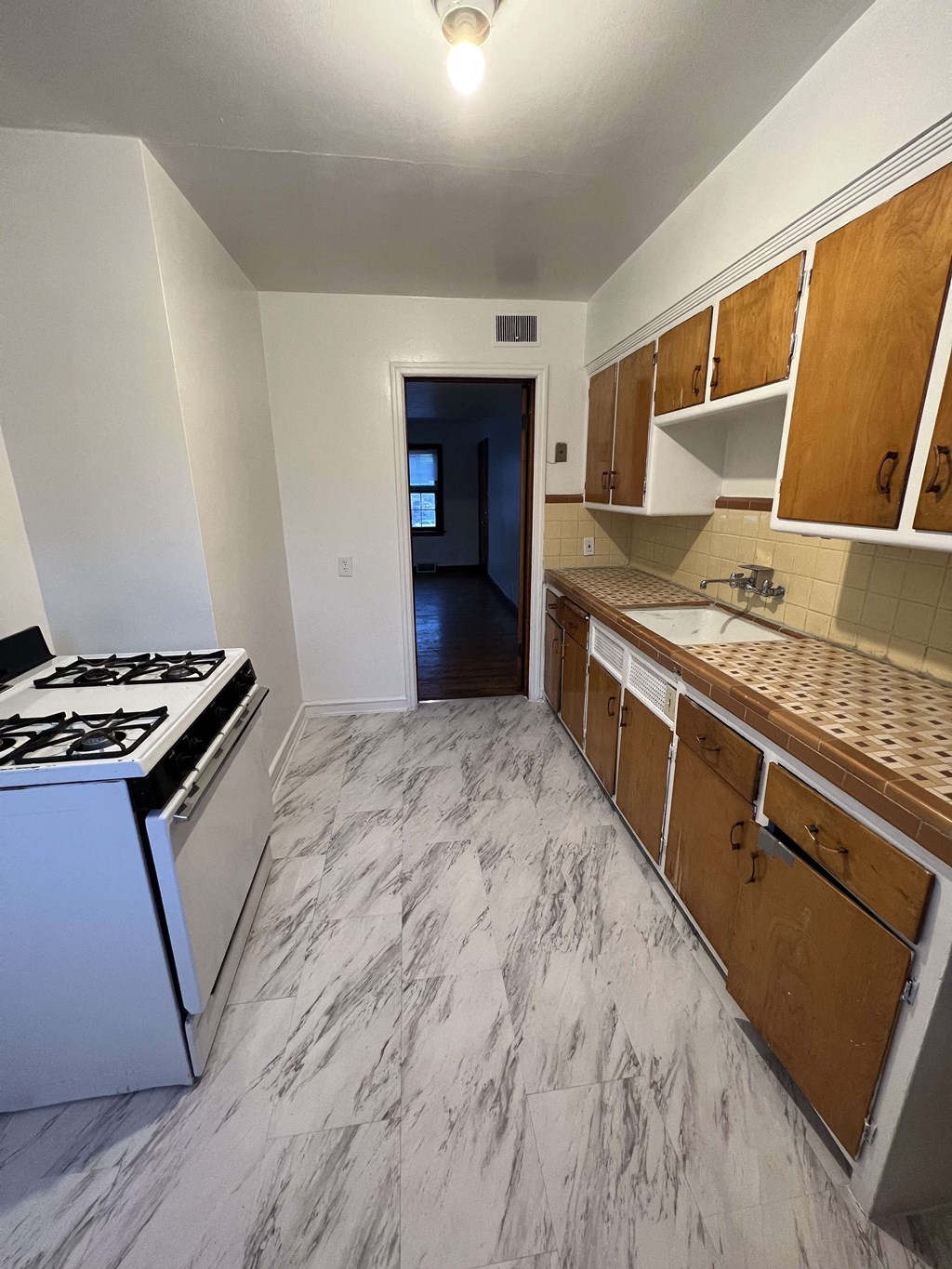 an empty kitchen with wood cabinets and a stove and a sink