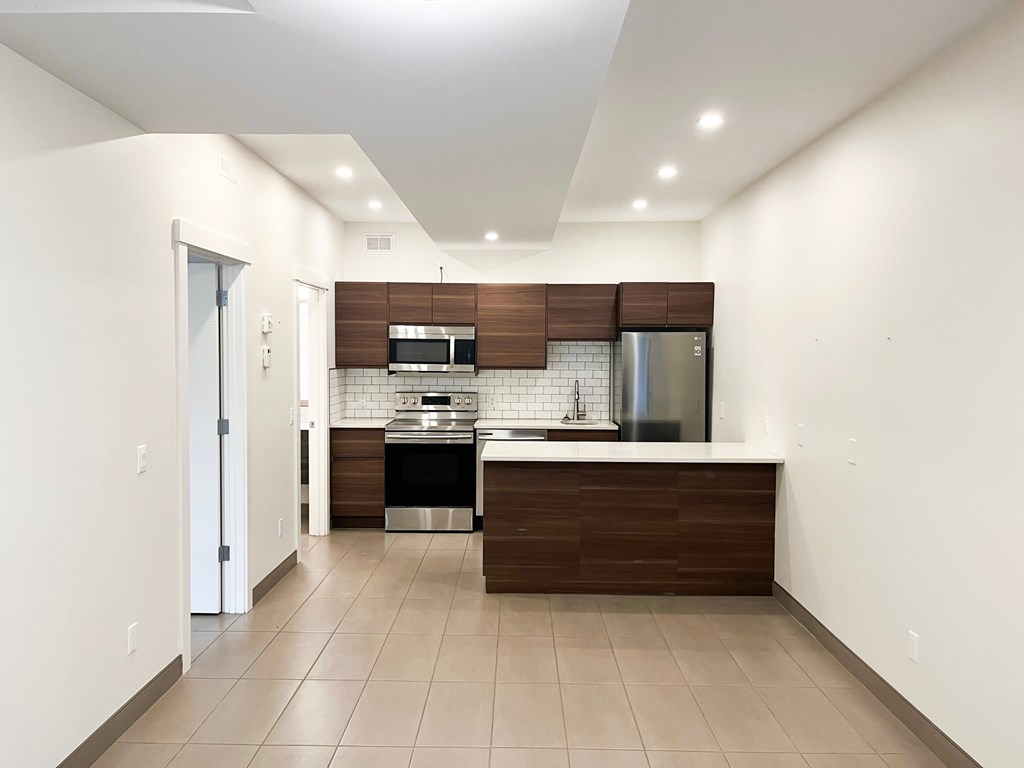 an empty kitchen with white walls and wooden cabinets