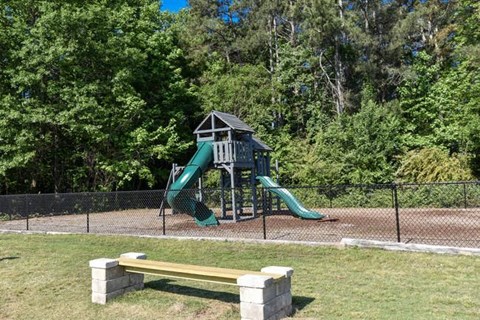 A playground with a green slide and a yellow bench.