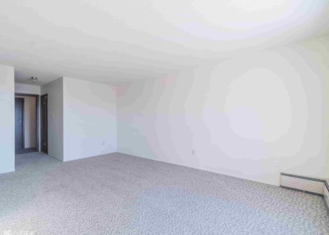 an empty living room with white walls and carpet