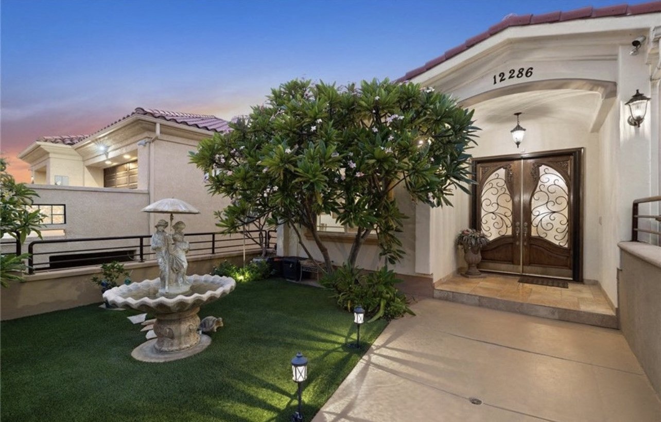 a mansion with a courtyard and a fountain in front of it