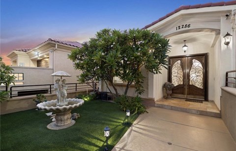 a mansion with a courtyard and a fountain in front of it