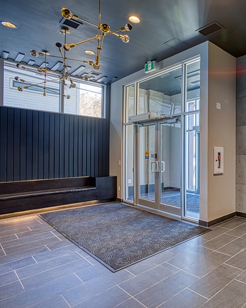 A hallway with a glass door and a carpet on the floor.