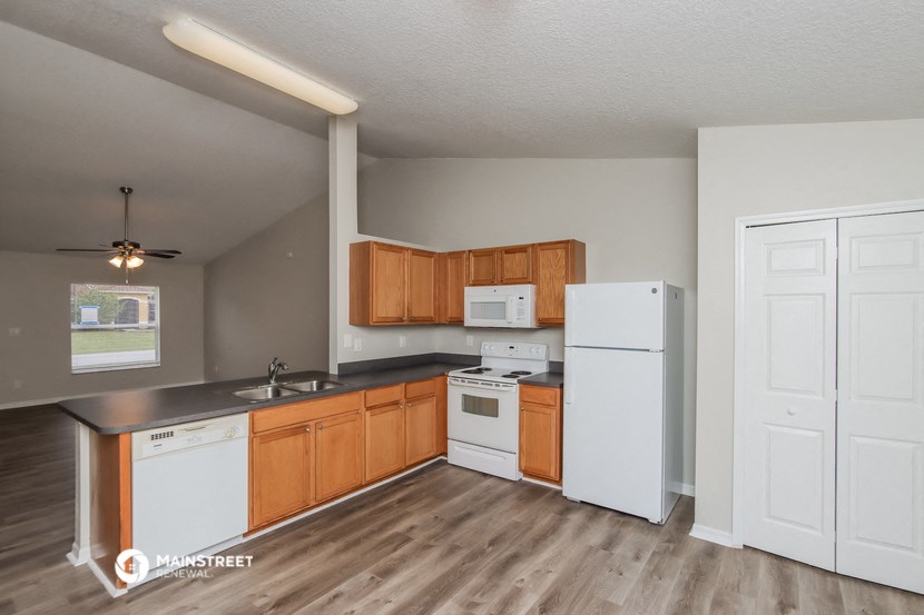 an empty kitchen with wood flooring and white appliances