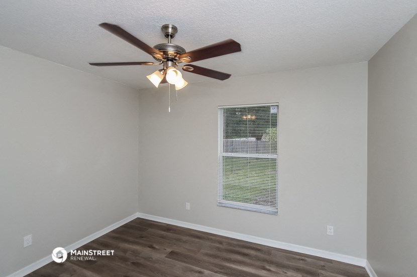the interior of a bedroom with a ceiling fan and a window