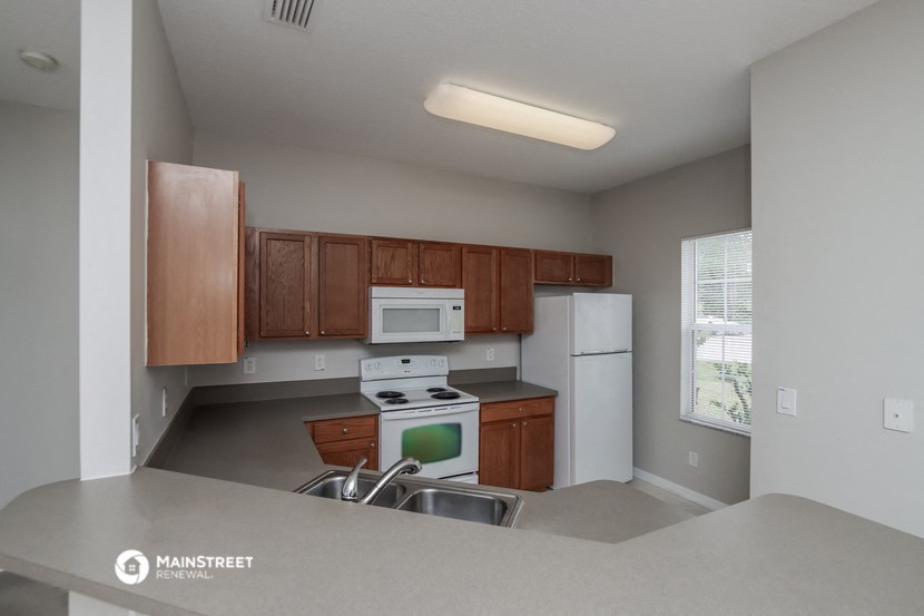 an empty kitchen with white appliances and wooden cabinets