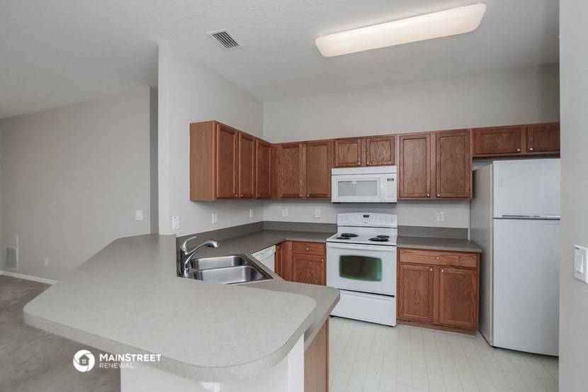 an empty kitchen with white appliances and wooden cabinets
