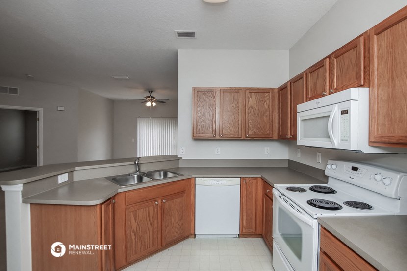 an empty kitchen with white appliances and wooden cabinets