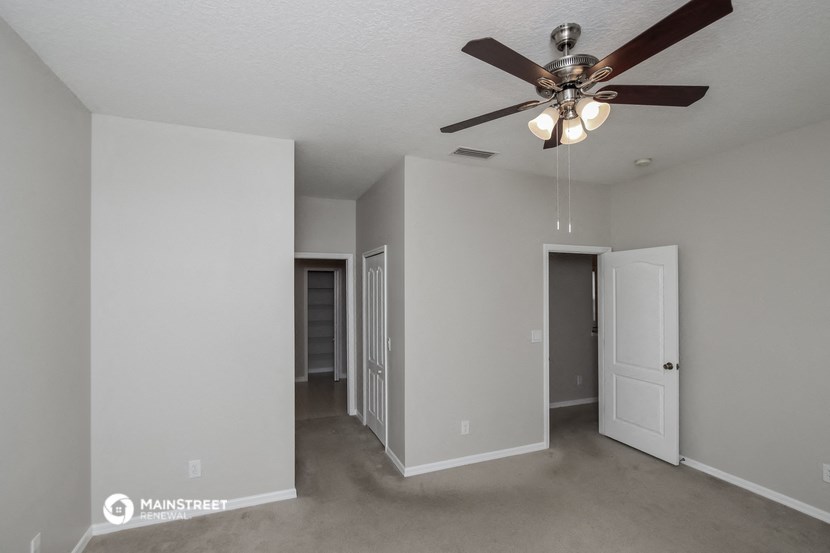 a living room with a ceiling fan and a door to a hallway