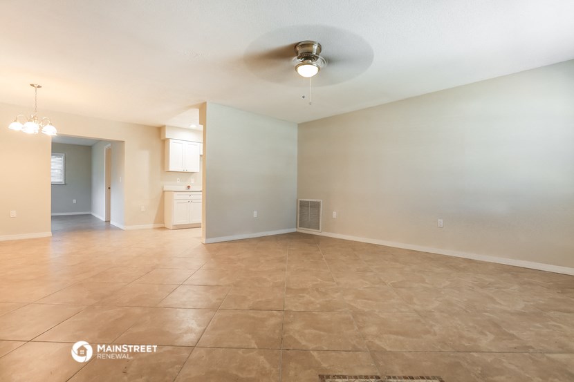 the spacious living room with tile flooring and a ceiling fan