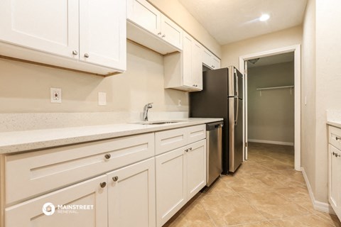 a kitchen with white cabinets and a black refrigerator
