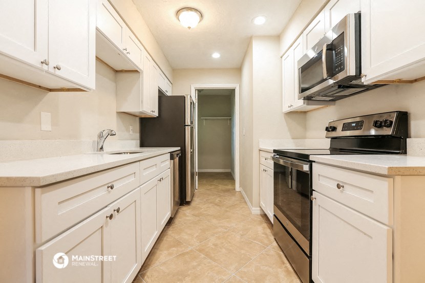 a kitchen with white cabinets and a black stove and a microwave