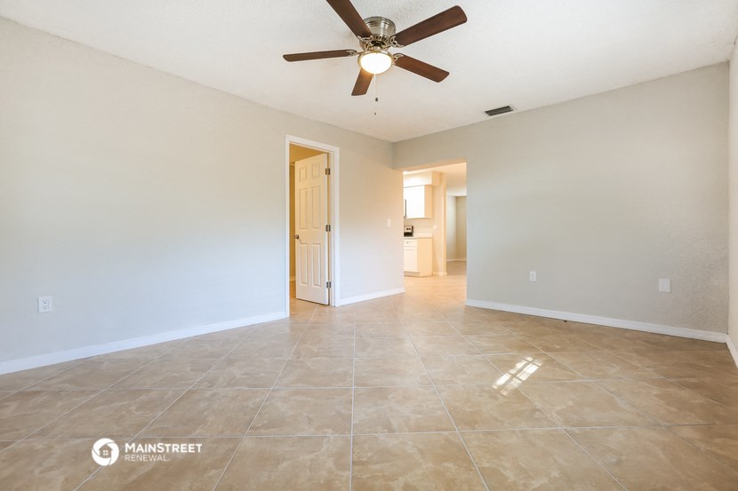 the spacious living room with tile flooring and a ceiling fan