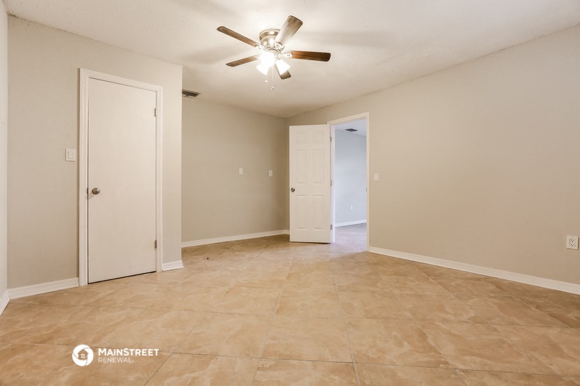 the spacious living room with ceiling fan and tile flooring