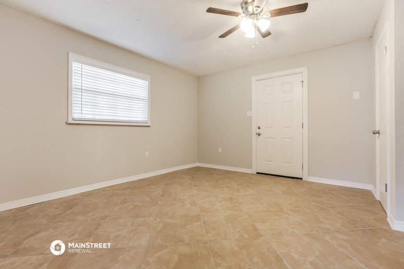 the spacious living room with a ceiling fan and tile flooring
