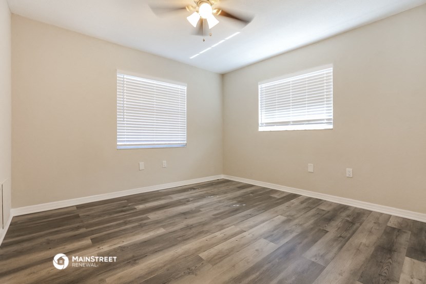 the spacious living room with hardwood floors and a ceiling fan