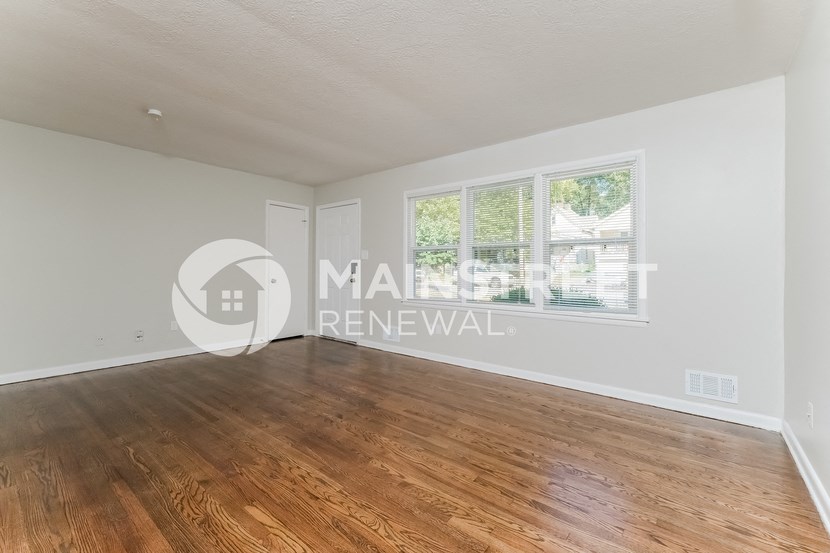 a renovated living room with wood floors and a large window