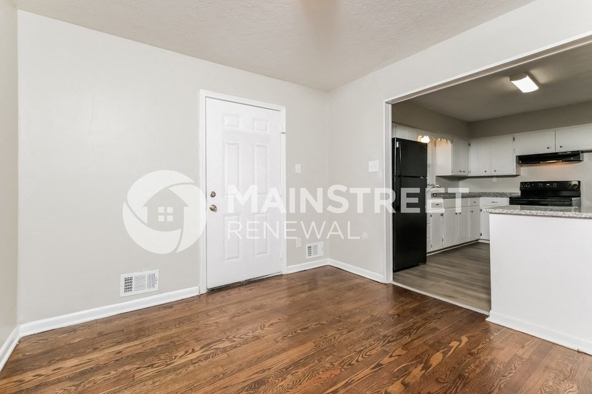 a living room and kitchen with hardwood flooring and a white door