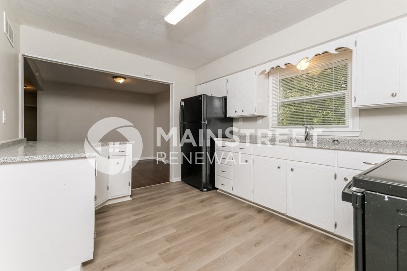 a white kitchen with white cabinets and a black refrigerator