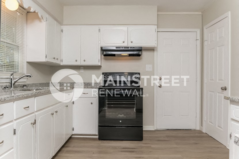 a renovated kitchen with white cabinets and black appliances