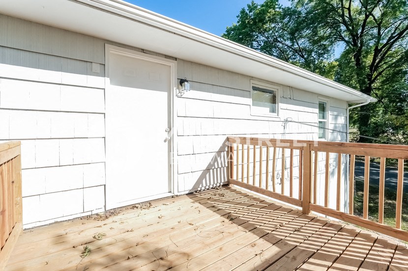 the deck of a house with a white garage door and a wooden railing