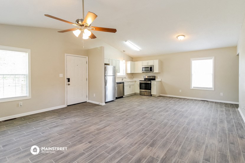 an empty living room and kitchen with a ceiling fan